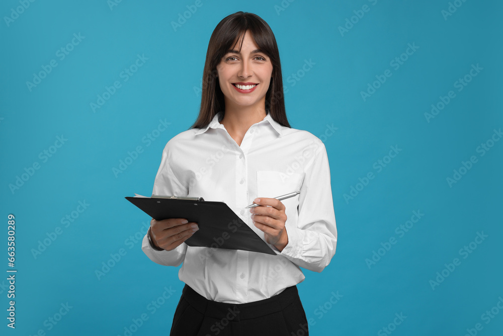 Happy secretary with clipboard and pen on light blue background Happy secretary with clipboard and pen on light blue background