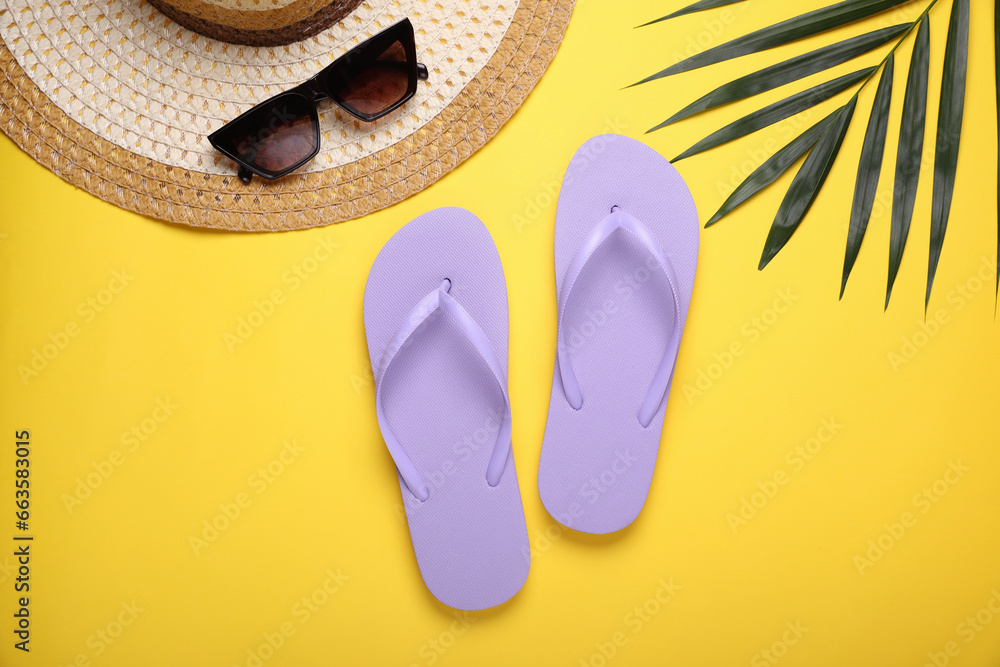 Stylish flip flops, sunglasses, hat and palm leaf on yellow background, flat lay Stylish flip flops, sunglasses, hat and palm leaf on yellow background, flat lay