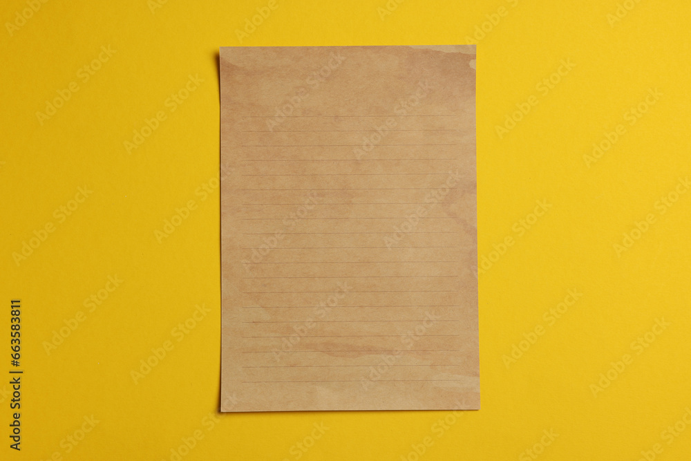 Fototapeta premium Sheet of old parchment paper on yellow background, top view