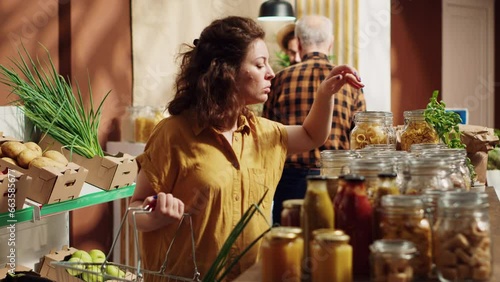 Vegan woman in specialty zero waste supermarket smelling bulk items before adding them to shopping basket. Client in local neighborhood shop testing to see if food is toxins free before buying it photo