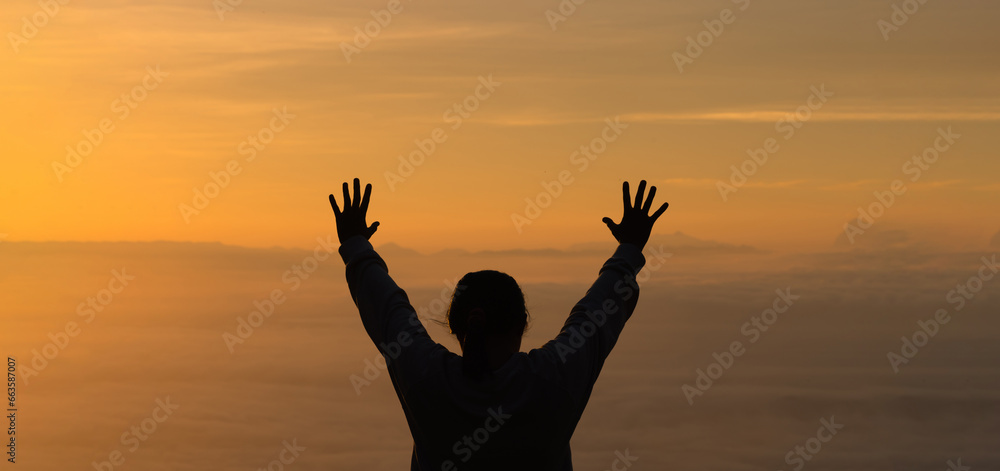 Woman raising his hands in worship. Christian Religion concept. Silhouette woman on sunrise background. Christian female prayers to God in faith. Women raise hands in praise with faith and peace.