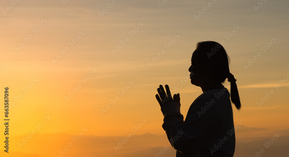 Woman raising his hands in worship. Christian Religion concept. Silhouette woman on sunrise background. Christian female prayers to God in faith. Women raise hands in praise with faith and peace.