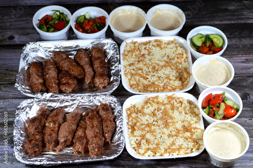 Arabic cuisine traditional food beef Kofta, kufta shish, minced meat wrapped in lamb fat charcoal grilled, with green and Tahini salad and hot steamed Egyptian white rice with vermicelli photo