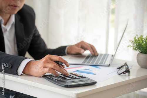 Close up man hands Asian businessman  calculating number, audit planning on business report Asian Business man hands using calculator counting tax financial bill. Tax audit Finacial concept photo