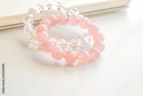 Rose quartz crystal bracelet and clear quartz bracelet on the table. Pink stone for healing and protection. Jewellery fashion design. 
