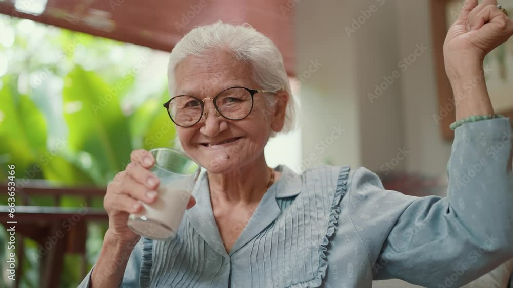 Attractive Asian elderly older drink a glass of milk in leisure time at home. Elderly woman drinking fresh milk in the morning for health care. Elderly older healthy lifestyle Attractive Asian elderly older drink a glass of milk in leisure time at home. Elderly woman drinking fresh milk in the morning for health care. Elderly older healthy lifestyle