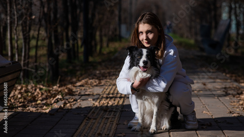 Caucasian woman hugging border collie in autumn park. Portrait of a girl with a dog.