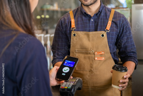 Man owner coffee shop submit an electronic cash register and coffee cup to woman customer, Female use phones scan payments through banking apps to pay for food and drink. pay with credit card. photo