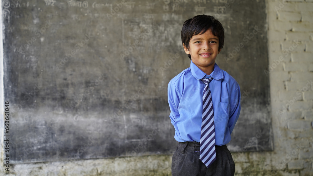 Indian school child sitting at desk in classroom with notebooks writing test Elementary school, Education concept. Indian school child sitting at desk in classroom with notebooks writing test Elementary school, Education concept.
