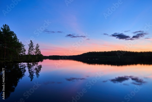 Scenic view of a tranquil lake at sunset © Wirestock