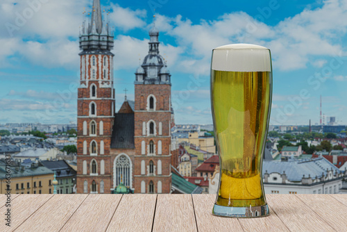 Glass of light beer on table in front of St. Mary's Basilica in Krakow, Poland photo