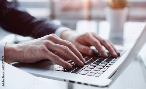 Closeup image of a man working and typing on laptop computer keyboard