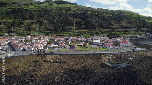 Drone pullback view of Lajes do Pico coastal village on rugged shoreline, Azores photo