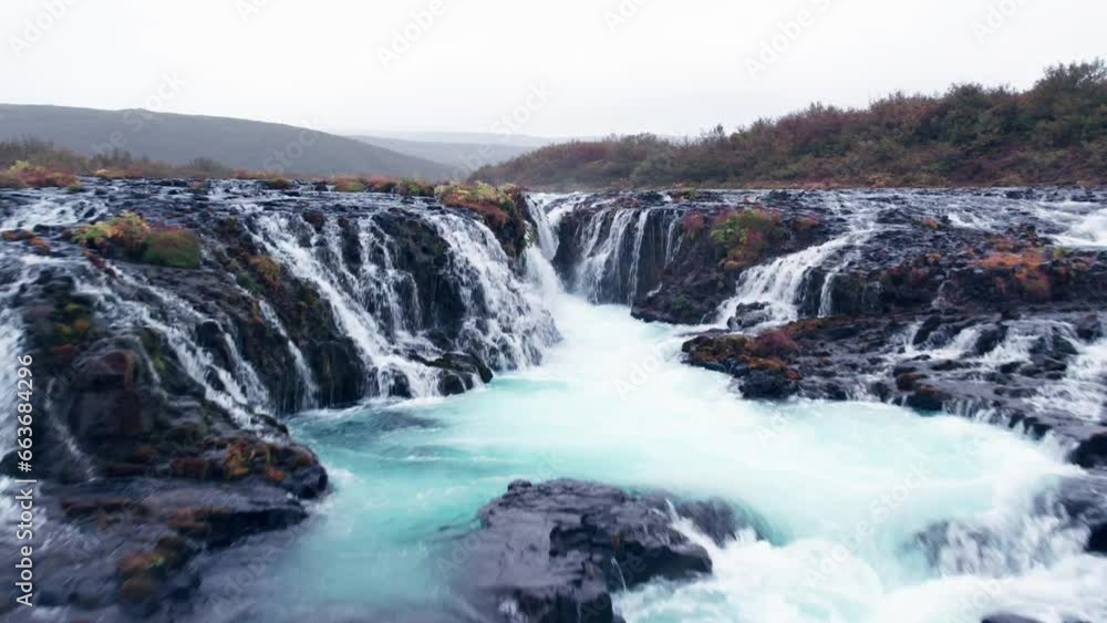 Aerial: Bruarfoss (Brúarfoss) cascading waterfall off the golden circle in southern Iceland that is very picturesque with the beautiful blue cascade of falls into the plunge pool below Aerial: Bruarfoss (Brúarfoss) cascading waterfall off the golden circle in southern Iceland that is very picturesque with the beautiful blue cascade of falls into the plunge pool below