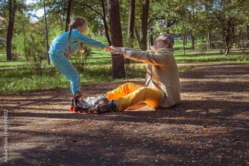 A girl roller skates in the park with her old grandfather. A funny grandfather and a little girl are playing and joking. A grandfather on roller skates plays pranks with his granddaughter. photo