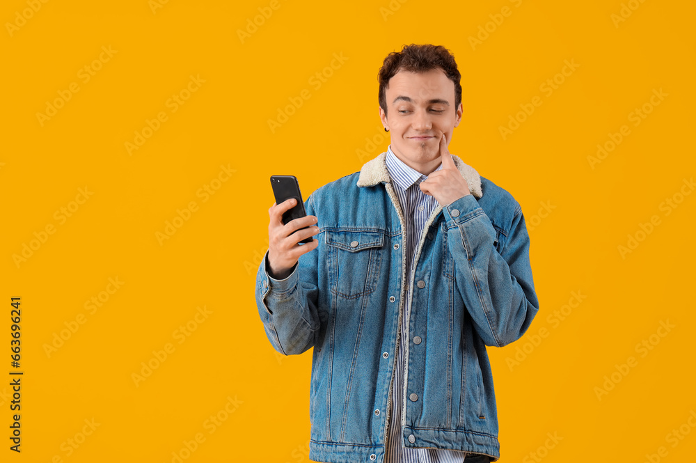 Cool young man with smartphone on yellow background Cool young man with smartphone on yellow background
