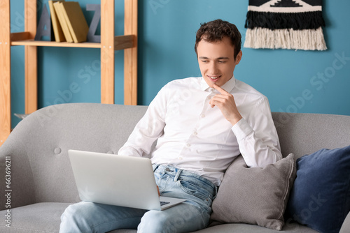 Young man with laptop sitti...