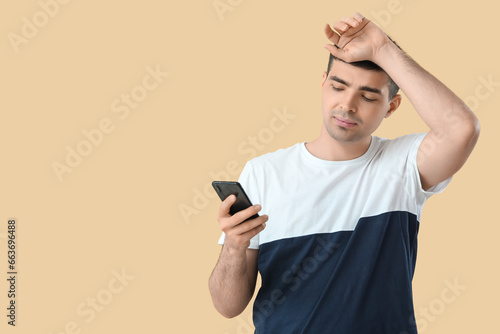 Tired young man with smartp...