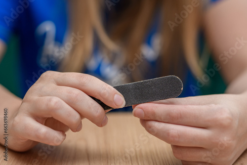 Kobieta poleruje swoje paznokcie pilniczkiem