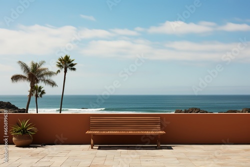 Bench on a terrace overlooking the ocean with palm trees and blue sky. Background with copy space