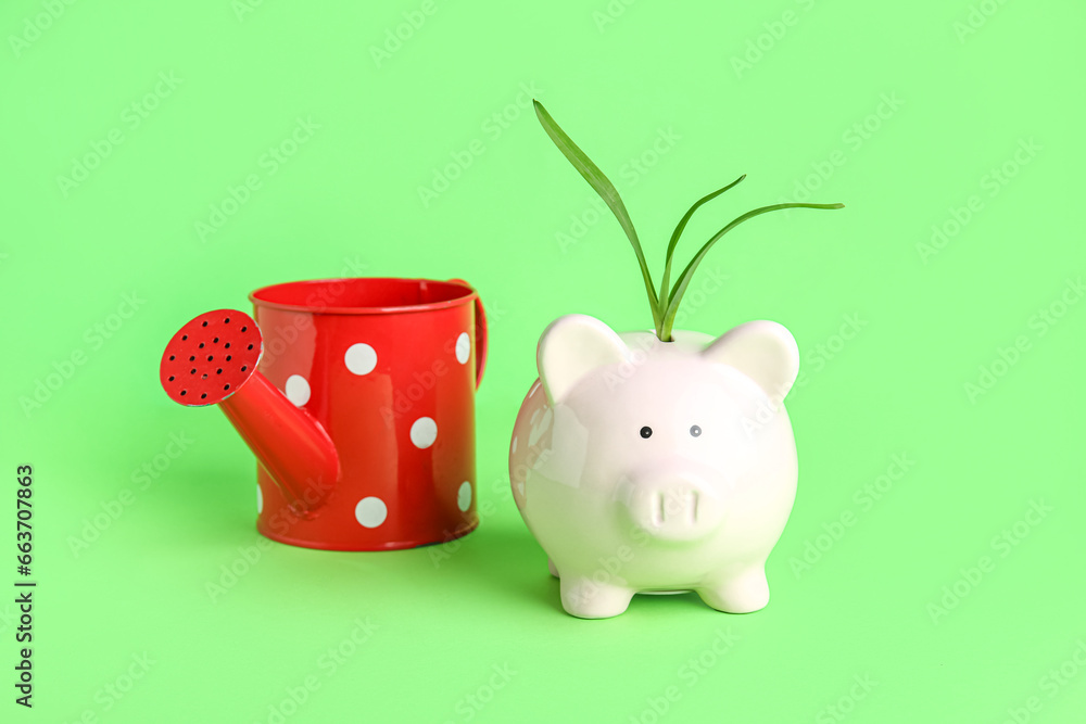 Plant growing from piggy bank and watering can on green background ...