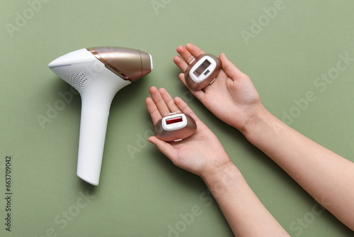Female hands with modern photoepilator attachments on green background