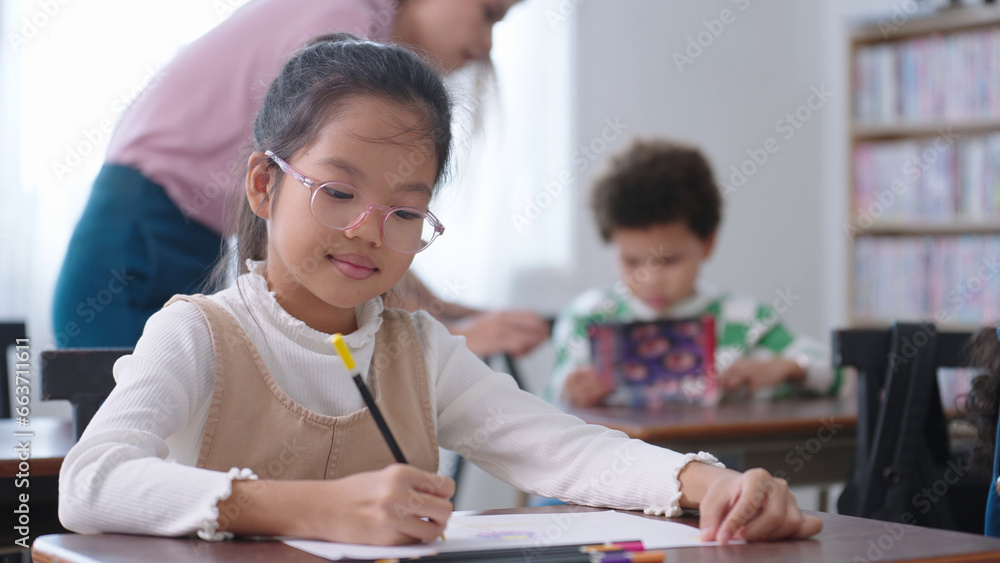 Asian school girl in glasses studying, writing notes in notebook at classroom. Schoolgirl studying and preparing for exams. little pupil writing at desk in classroom. Education knowledge concept Asian school girl in glasses studying, writing notes in notebook at classroom. Schoolgirl studying and preparing for exams. little pupil writing at desk in classroom. Education knowledge concept