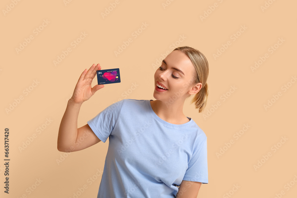 Pretty young woman with credit card on beige background Pretty young woman with credit card on beige background