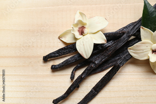 Aromatic vanilla sticks and flowers on wooden background