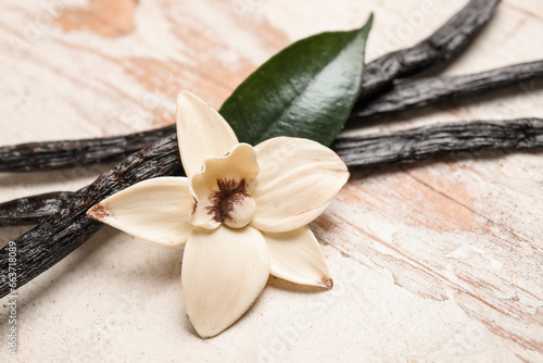 Aromatic vanilla sticks and flower on white wooden background