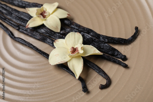 Aromatic vanilla sticks and flowers on brown background