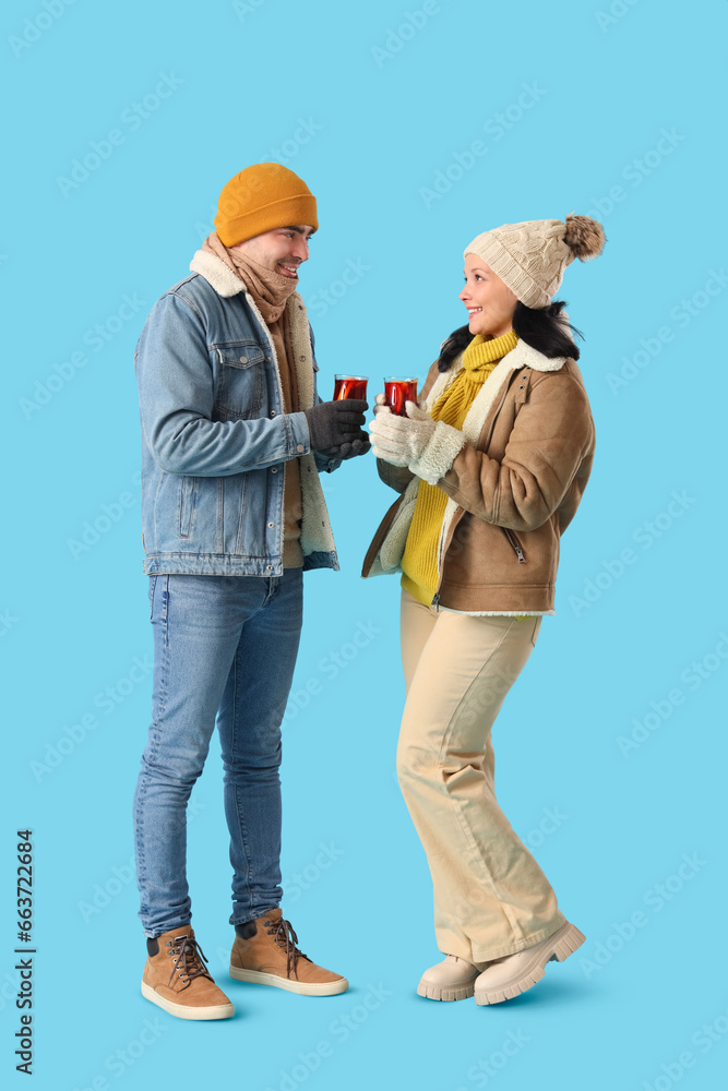 Young couple with glasses of mulled wine on blue background Young couple with glasses of mulled wine on blue background