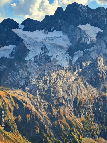 Snow-Capped Mountains with Green and Dry Grass, Clouds, and a Stunning Sky