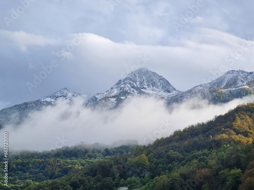 Snow-Capped Mountains with Green and Dry Grass, Clouds, and a Stunning Sky