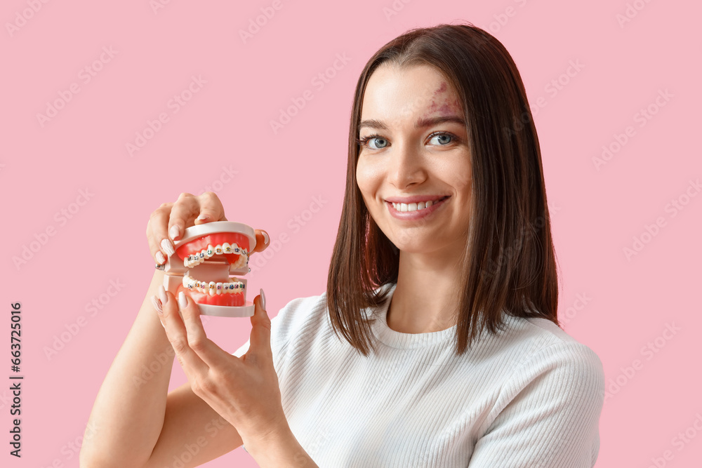 Smiling young woman with jaw model on pink background, closeup Smiling young woman with jaw model on pink background, closeup
