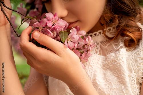 young woman smell pink flowers of  blooming apple tree on branch in spring