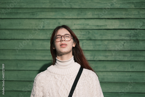 Fototapet Teenage girl stands with eyes closed, illuminated by bright blinding sunlight