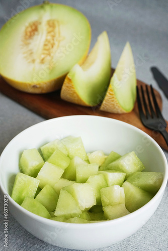 Sliced ​​juicy melon on a wooden board on a gray background