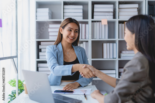 Two young Asian businesswoman handshake successful with a colleague in the office.