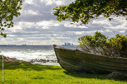 
The bow of a wooden boat on the shore against the background of the city and the sea photo
