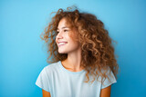 Woman with curly hair smiling and looking up at the sky.