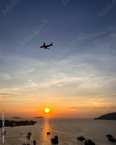 Valokuva a view of the sun setting at sea with an airplane flying over it