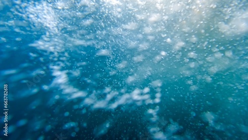 Fast river current with lots of air bubbles and vortexes shot underwater in clear blue water
