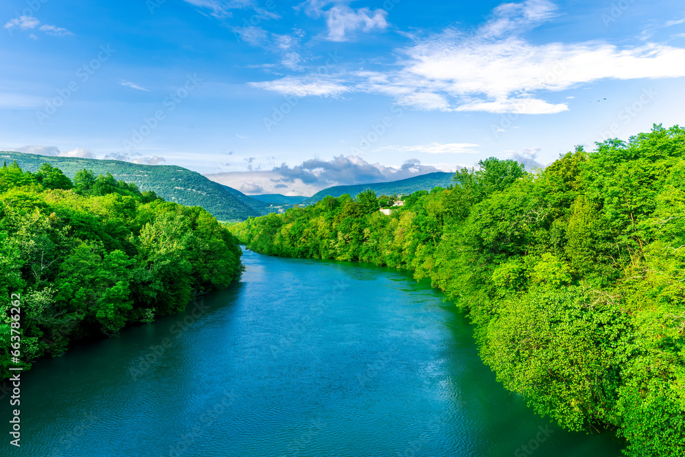 beautiful landscape of spring or summer sunset river with blue water and green hills on sides and mountains with amazing cloude sky on background