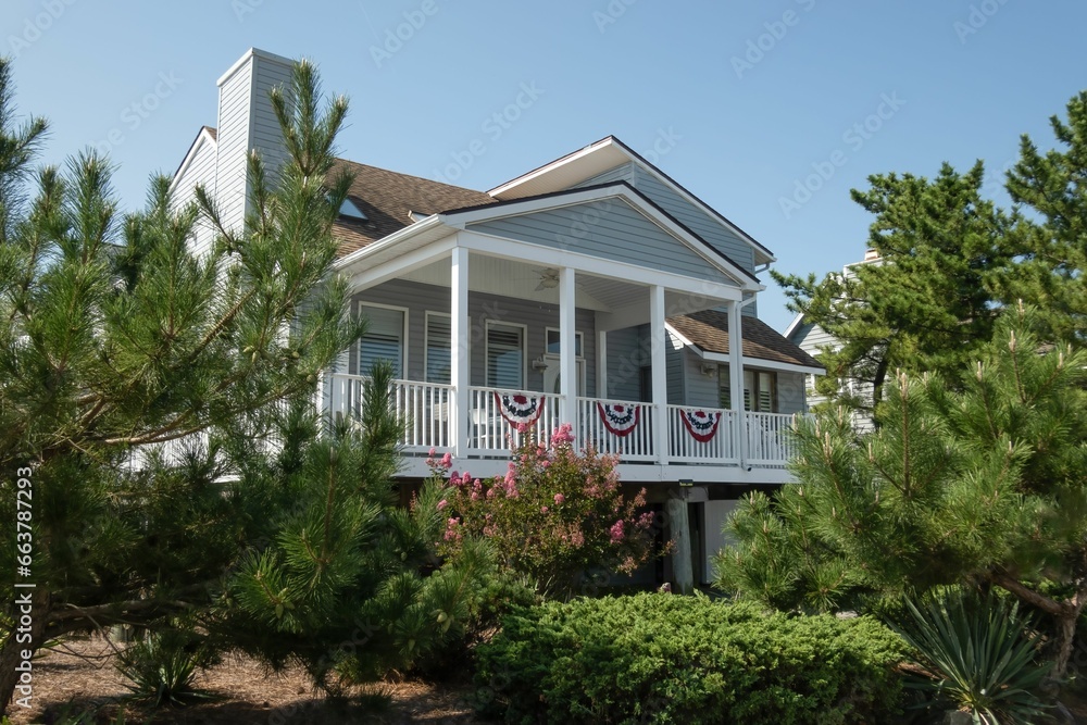 a large house with two decks on top of it, next to shrubs and trees