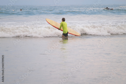 Surfer on the beach goes into the ocean