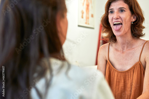 middle age female patient shows tongue to nurse for prescription at healthcare center. 