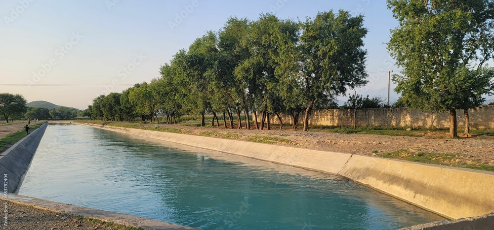 Peaceful, rural scene with a water canal running alongside a dirt road