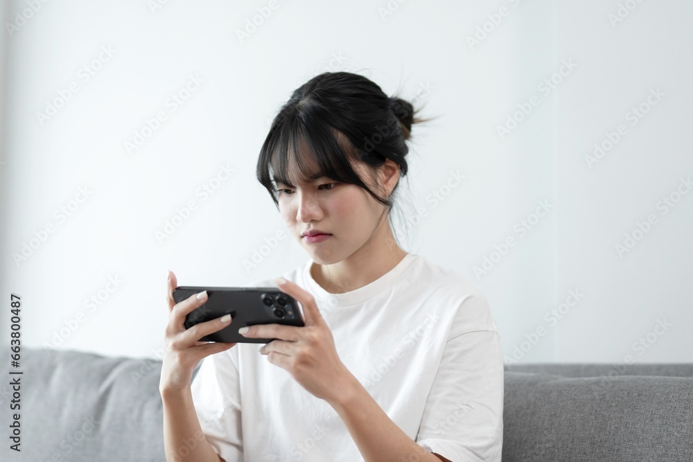 Asian woman playing game on mobile phone. gamer girl playing video games holding Smartphone working mobile devices. cell telephone technology e-commerce concept Asian woman playing game on mobile phone. gamer girl playing video games holding Smartphone working mobile devices. cell telephone technology e-commerce concept