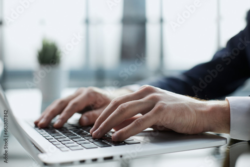 Closeup image of a man working and typing on laptop computer keyboard